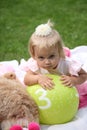 Sweet smiling little girl with long blond hair, sitting on grass in summer park, closeup outdoor portrait. Royalty Free Stock Photo